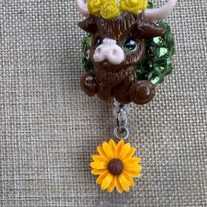 Brown highland cow badge reel with green rhinestones and sunflowers